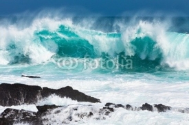 Fototapety Turquoise rolling wave slaming on the rocks