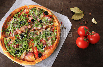 Pizza with arugula on color wooden background
