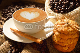A cup of cafe latte with coffee beans and cookies