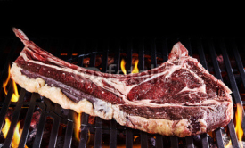 Obrazy i plakaty Single raw tomahawk steak piece on grill