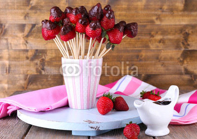 Strawberry in chocolate on skewers in cup on table close-up