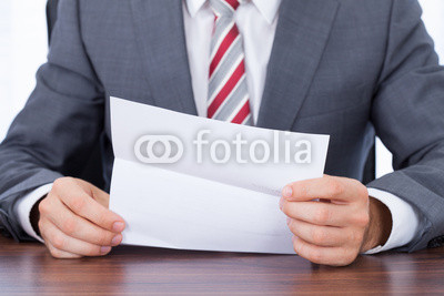 Businessman Reading Document At Desk