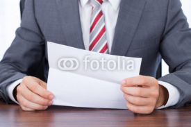 Obrazy i plakaty Businessman Reading Document At Desk