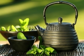 Naklejki Black iron asian teapot with sprigs of mint for tea