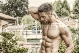 Handsome shirtless muscular young man outdoor, looking at camera