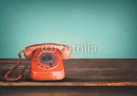 Old retro red telephone on table with vintage green pastel background