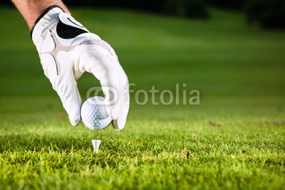 Hand hält Golfball auf Golfplatz mit Tee
