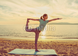 Naklejki Young woman practicing yoga on beach