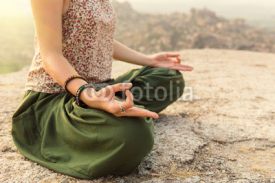 Young woman meditating at mountain cliff on sunrise. Hands close-up