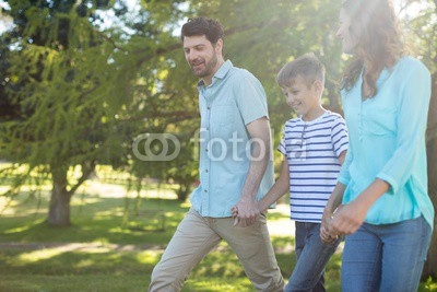 Happy family with hand in hand walking in park