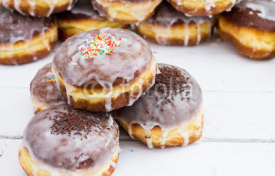 Fototapety Stack of donuts with color glaze. Composition on white wooden bo