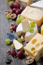 Fototapety cheeses, grapes and walnuts on a wooden background, top view