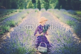 Naklejki Woman in purple dress and hat with basket in lavender field