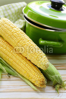 ripe yellow corn and green pan on a wooden background