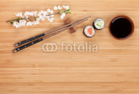 Sushi maki with fresh sakura branch over bamboo table