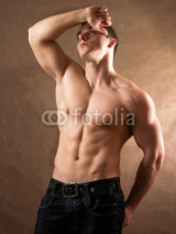 Fototapety Portrait of a naked muscular man, isolated on beige background