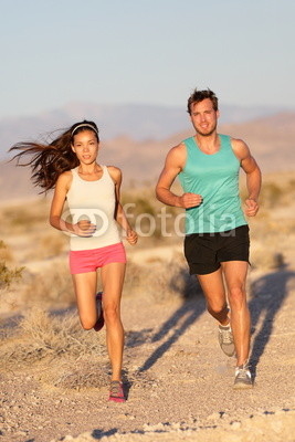 Running couple - runners jogging on trail run path