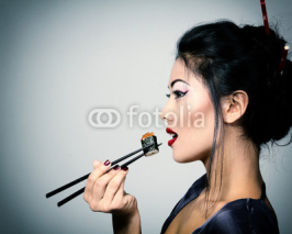 Obrazy i plakaty Young beautiful asian woman eating sushi with chopsticks, toned