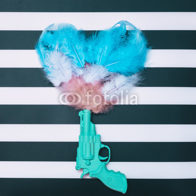 feathers in form of heart fly out of the gun on striped background
