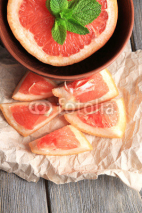 Fototapety Part of ripe grapefruit in bowl, on wooden background