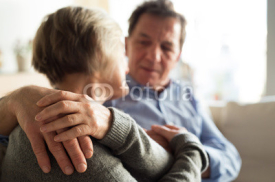 Senior couple sitting on a couch in living room, hugging