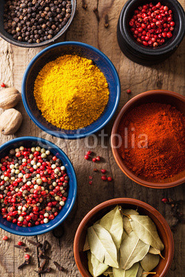 spices in bowls: pink black pepper, paprika powder, curry, bay l