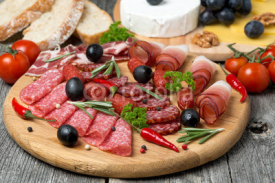 Naklejki Assorted meats and sausages on a wooden board