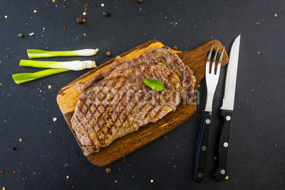 Grilled beef steak served on a wooden board.