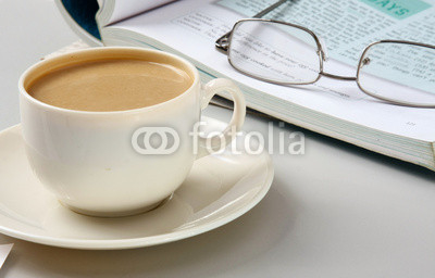 Cup of coffee near the laptop and newspapers