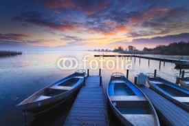 Obrazy i plakaty Peaceful sunrise with dramatic sky and boats and a jetty