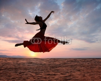 Jumping woman at sunset