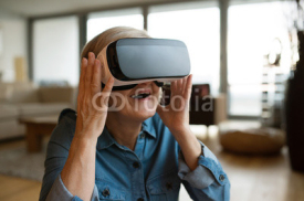 Senior woman wearing virtual reality goggles at home