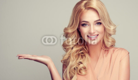
    Blonde woman with curly hair shows your product . .Beautiful girl with beautiful smile pointing to the side . Presenting your product. Expressive facial expressions