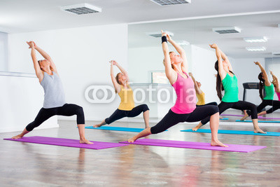 Four girls practicing yoga, Virabhadrasana / Warrior pose