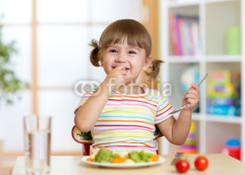 Funny little girl eating healthy food in kindergarten