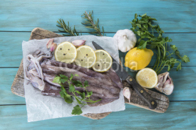 Obrazy i plakaty Calamares frescos en la mesa con ingredientes para cocinarlos