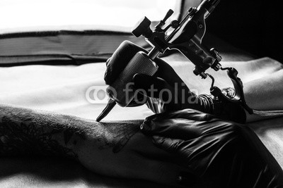 Tattooist makes tattoo on clients arm in bw