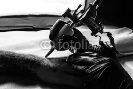 Naklejki Tattooist makes tattoo on clients arm in bw