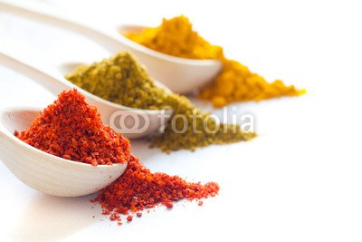 Spices in wooden spoons on a white background closeup