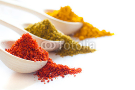 Fototapety Spices in wooden spoons on a white background closeup