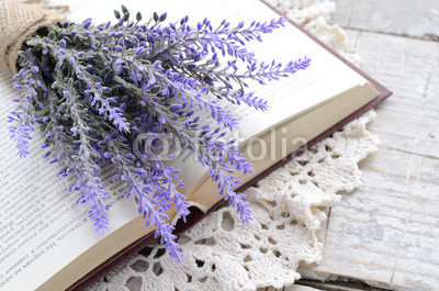 Bunch of lavender laying upon open book on vintage doily