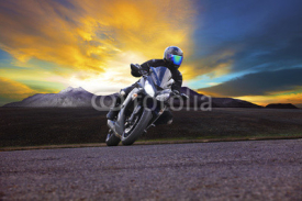 Naklejki young man riding motorcycle in asphalt road curve with rural and