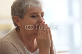 Praying elderly woman at home