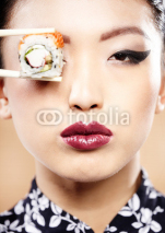 Fototapety Beautiful young woman eating sushi. Shallow depth of field, focu