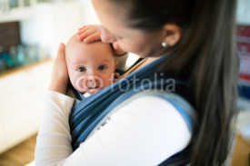 Mother at home with her son in sling, stroking him