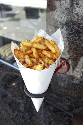Potatoes fries in a little white paper bag hanging at the wall f