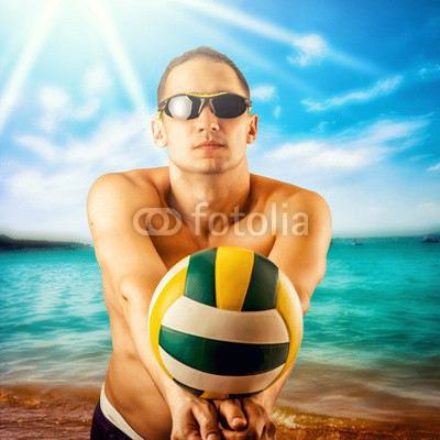 young man playing volleyball on the beach