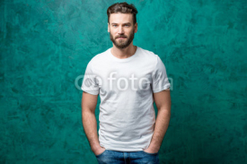 Man in the white t-shirt with space to copy paste standing on the green wall background.