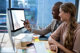 Graphic designer working at desk with colleague