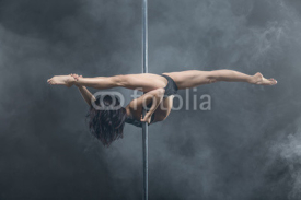 Female pole dancer posing in dark studio